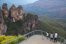Family enjoying views across Blue Mountains National Park to the Three Sisters and Mount Solitary from Echo Point Lookout.